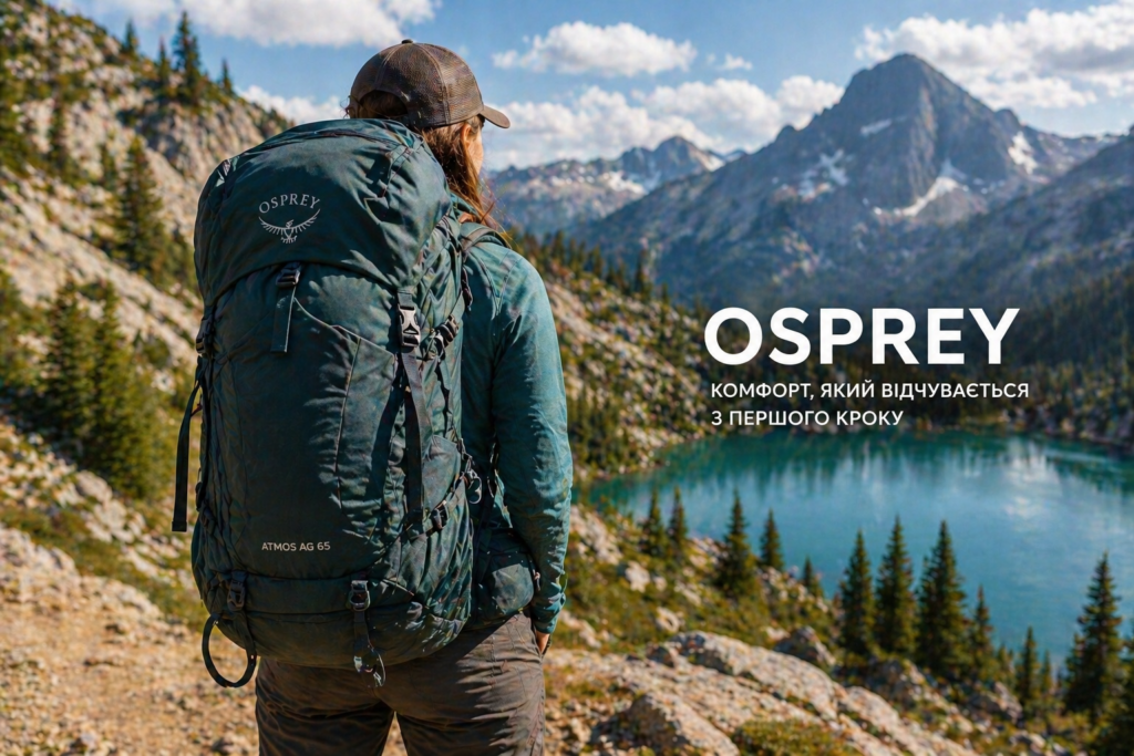 Hiker with a large teal Osprey backpack overlooking a turquoise alpine lake and rugged mountains.