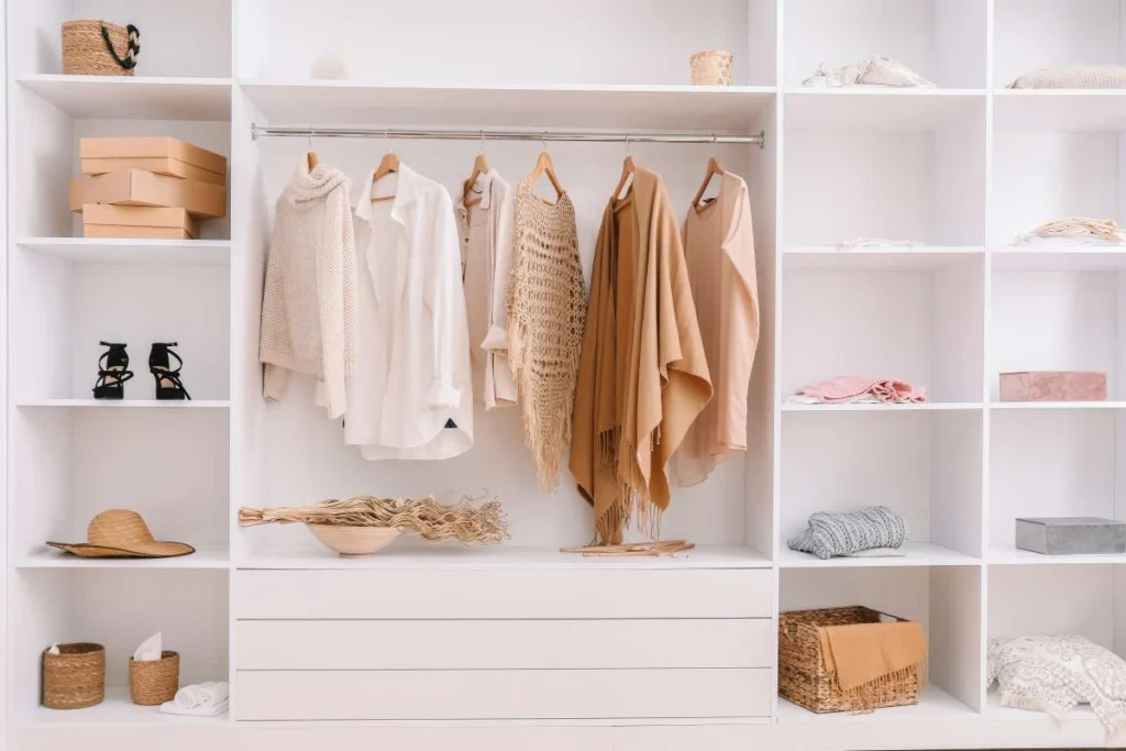 Neatly organized white wardrobe with hanging beige and white clothes and shelves with boxes, hats, and baskets. Як створити дорогий гардероб без переплат: секрети вибору ДСП і фасадів