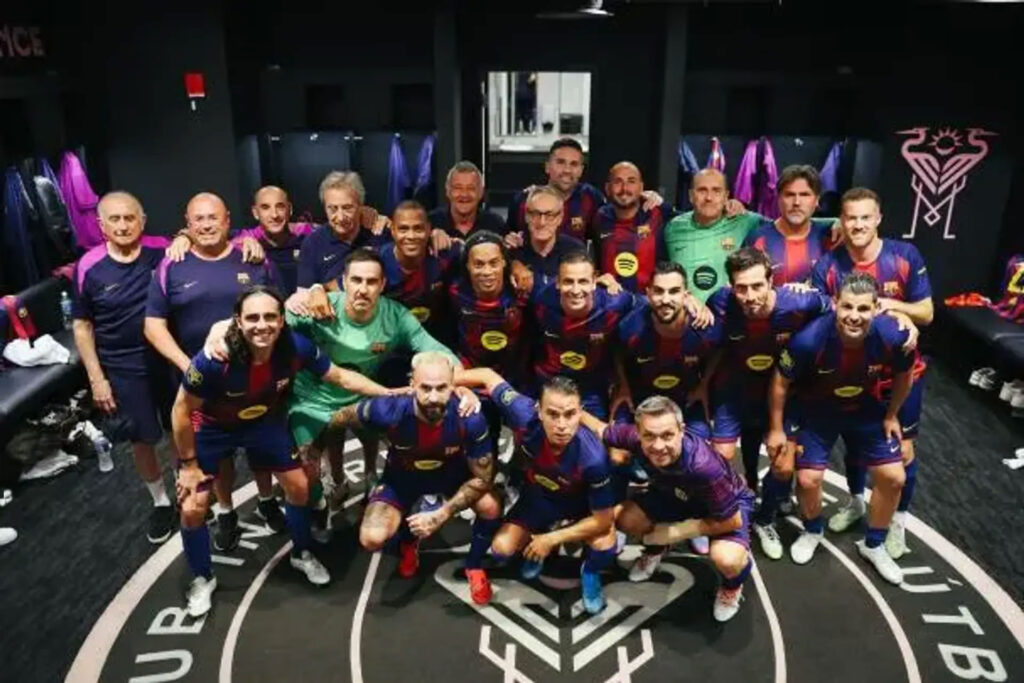 Soccer team photo: players in blue and maroon kits pose together in a locker room, arms around each other, with a team logo on the floor. Легенди Барселони і Реала зіграли в Майамі