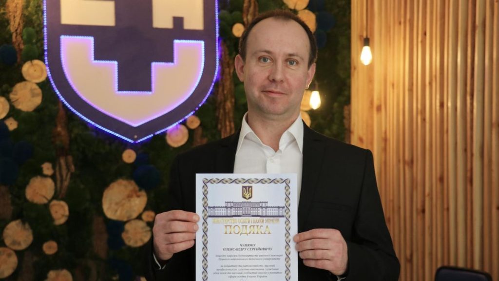 символічна сцена з партою викладача, купюрами доларів, ручкою та судовим документом
