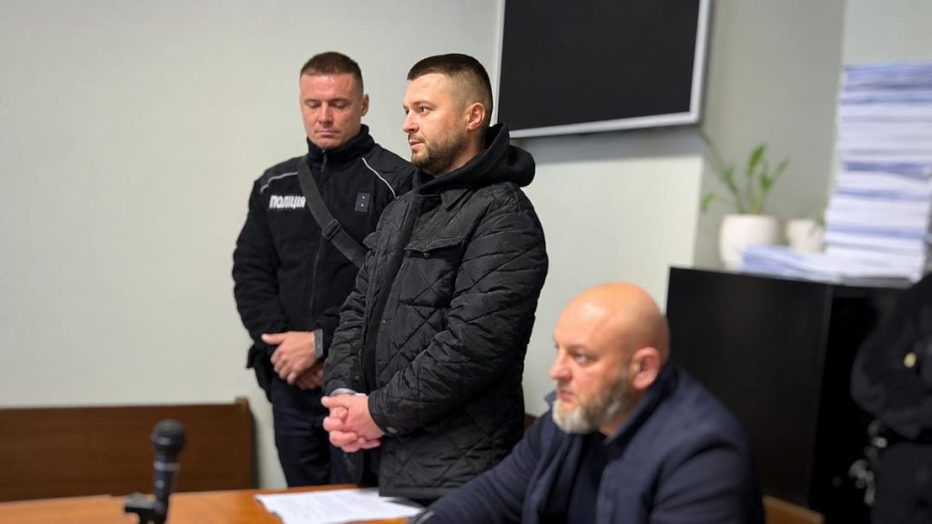 крупний план ключа від авто на судових паперах зі шальками правосуддя на дерев’яному столі