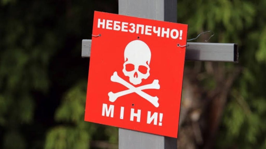 Пошкоджений трактор у лісовій галявині без людей, з обрубками і розкиданими інструментами