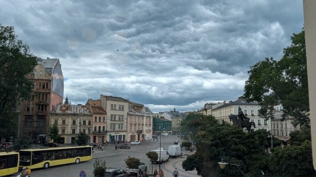 Парасоля, що тріпоче на вітрі, мокре листя та вінтажний термометр на нейтральній поверхні