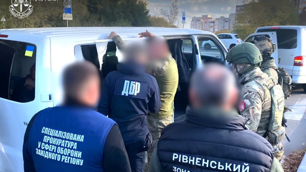 символічна предметна сцена: камуфльований одяг, жетон та кілька доларів на дерев'яному столі