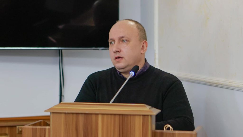 Молоток і офіційні документи на столі з розмитим прапором України на задньому плані