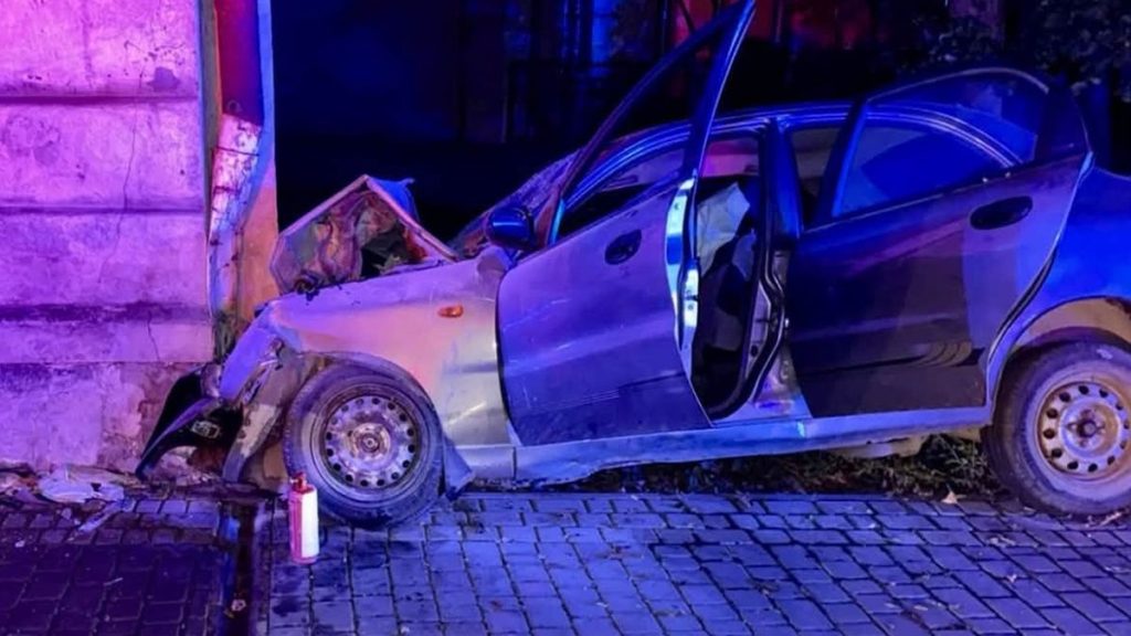 символічне фото понівеченого бампера та битого скла на асфальті під ліхтарем вночі