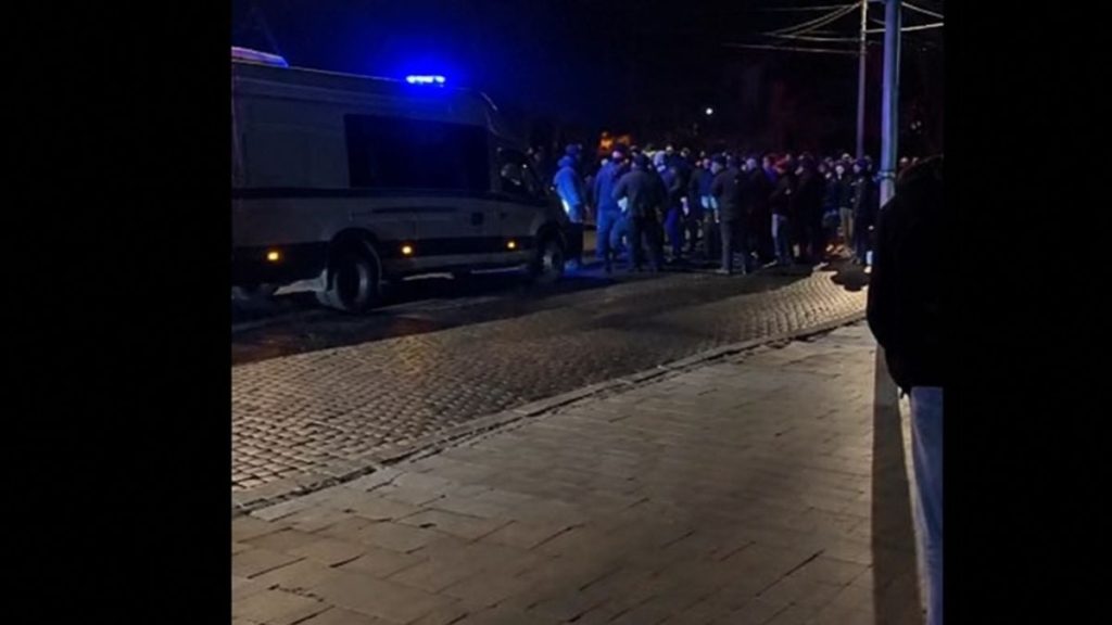 крупний план порожніх пляшок і поліцейської кепки на мокрому тротуарі вночі