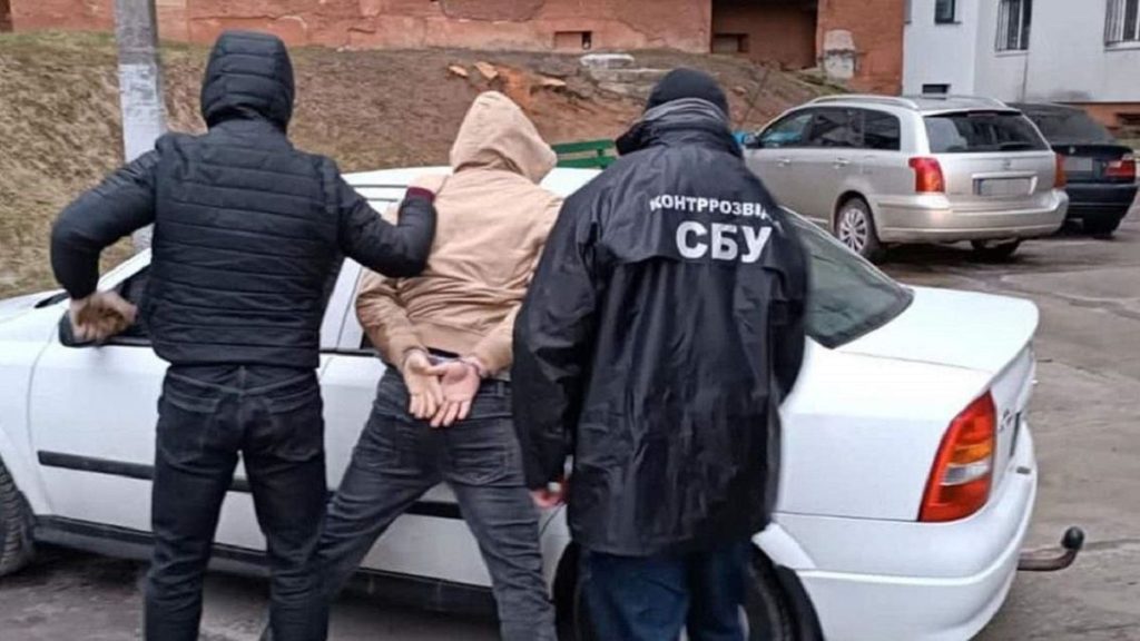 символічна натюрмортна сцена з молотком судді, українським прапором і папкою на дерев'яному столі