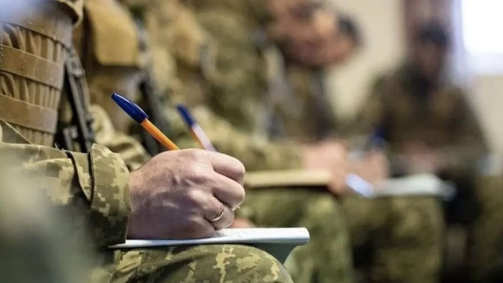 Крупний план: шолом, прапор України та гривні на дерев'яному столі
