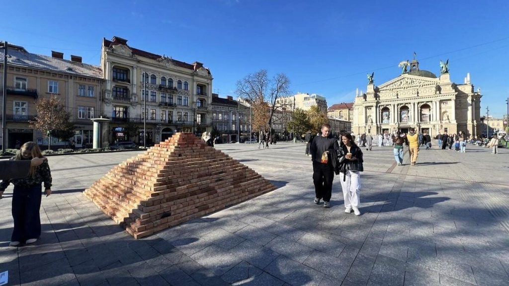 Кадр із пірамідою з цеглинок та дерев’яною інсталяцією з відкритою верхівкою в міському середовищі