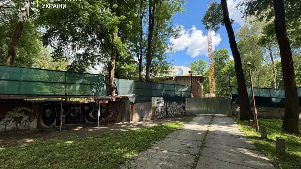 символічна композиція: частина паркану в парку, будівельні відходи і судовий документ