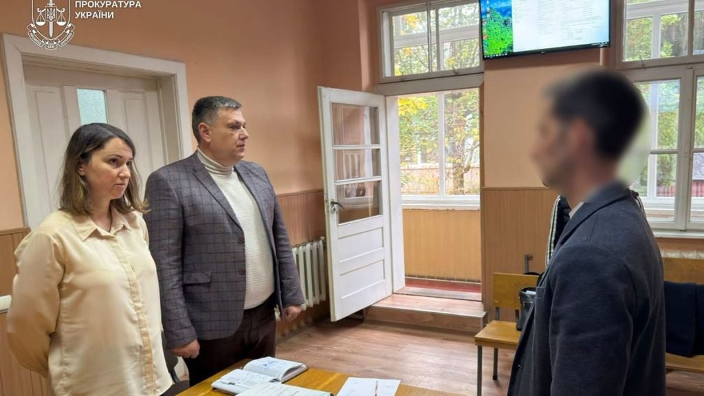 символічна сцена: закрита відеокамера на дерев'яному столі на фоні розмитого озера, без людей