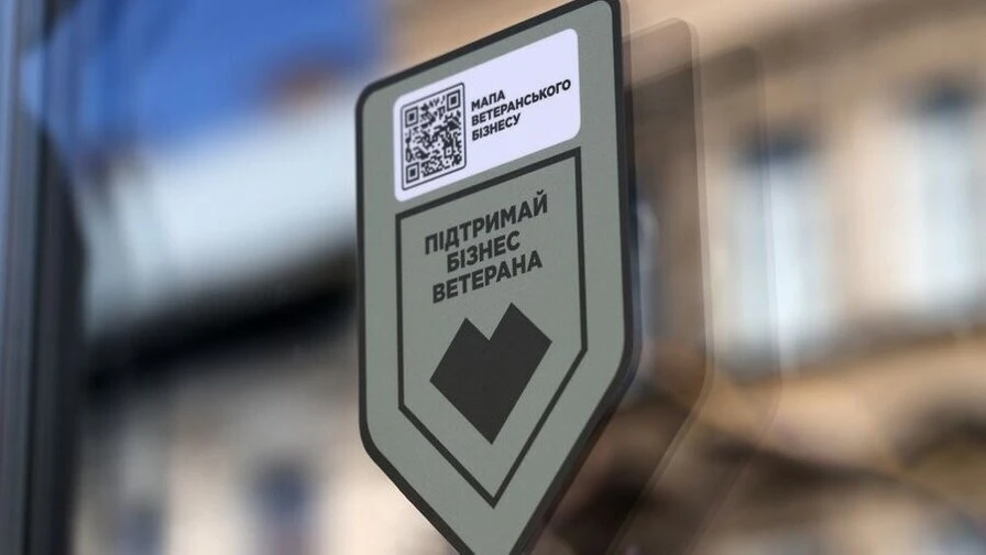 символічна натюрмортна сцена: чашка кави, планшет із простою картою, наліпка з QR-кодом, візитки на дерев'яному столі