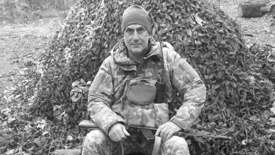 Футболка і військовий кітель на порожній лавці, медальйони та шолом поруч, символічна сцена без облич