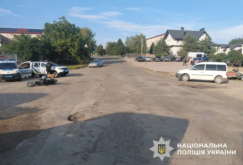 символічна композиція з помʼятою дверкою авто та мотоциклетним шоломом на узбіччі, без людей