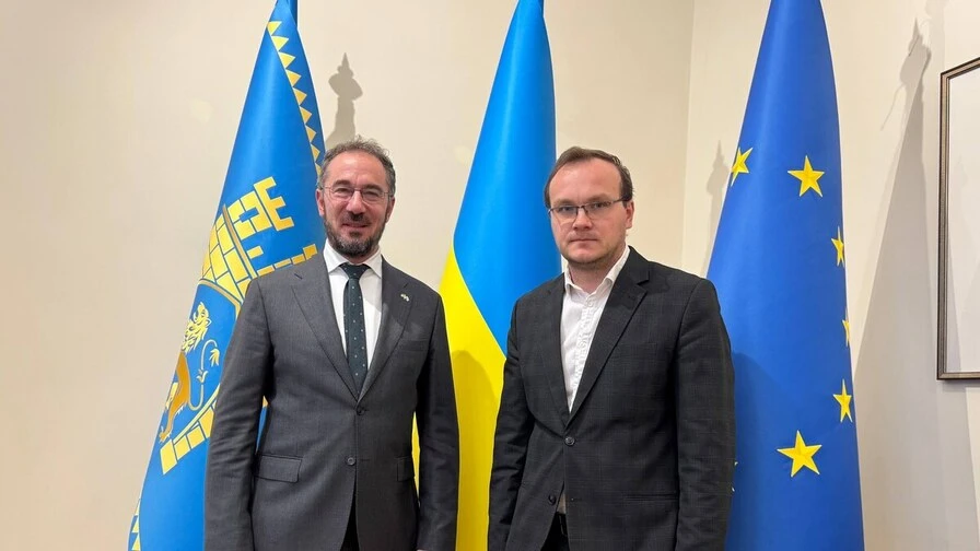 крупний план: грецький прапорець поруч з архітектурними кресленнями та чашкою кави