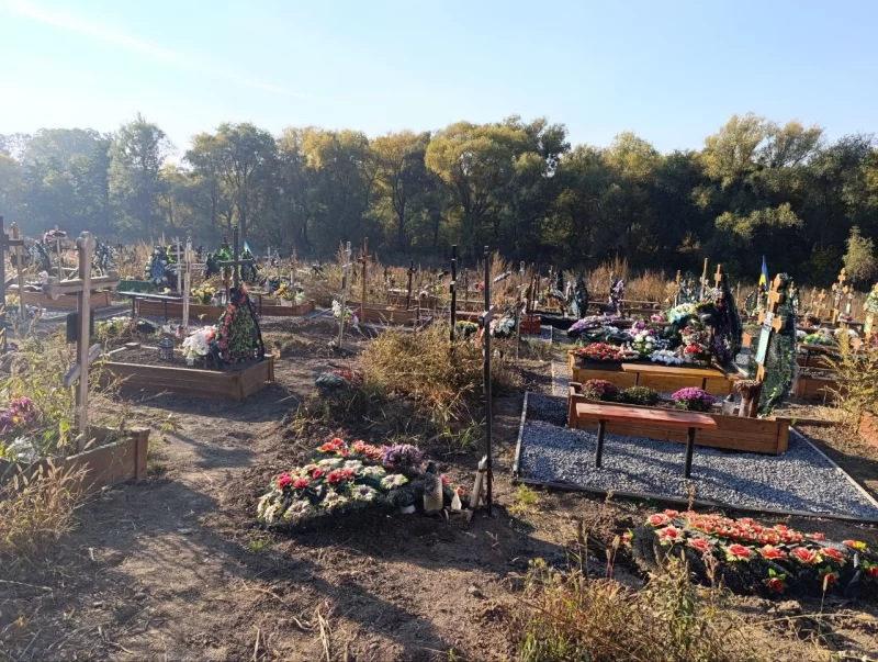 символічна сцена цвинтаря восени без людей, з опалим листям і похоронними предметами