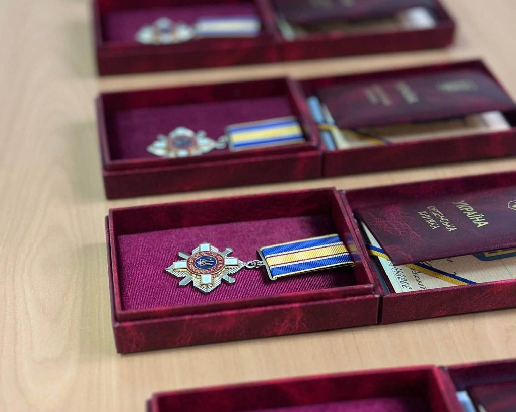 символічна сцена з нагородами та складеним синьо-жовтим полотнищем на темному дерев'яному тлі