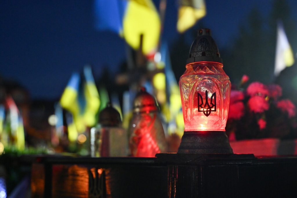 крупний план запалених скляних лампадок на надгробному камені з осіннім листям