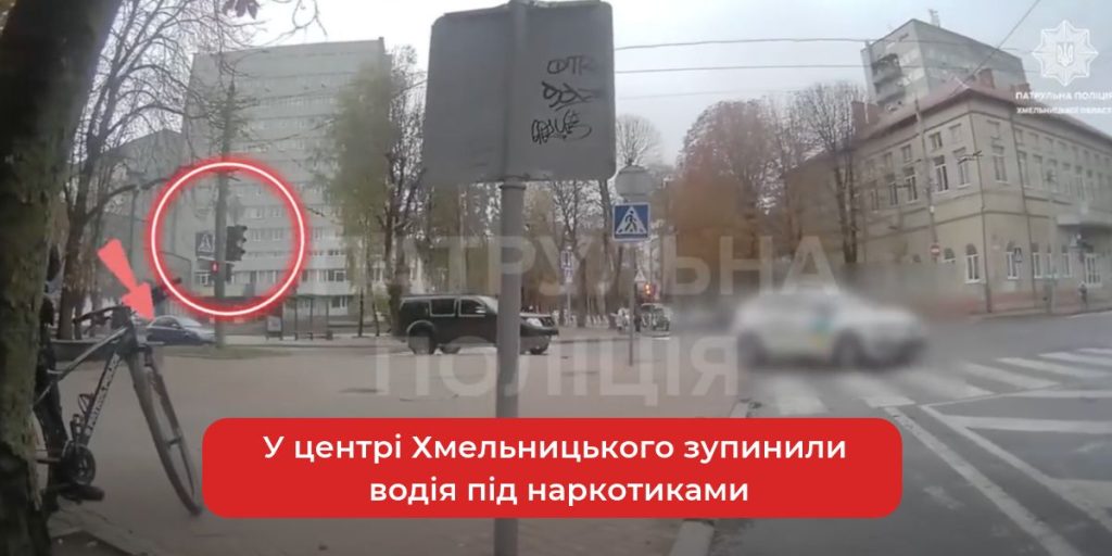 мінімалістична сцена: припаркований хетчбек біля перехрестя, розмитий жовтий сигнал світлофора