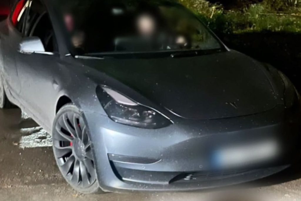 символічна сцена: Tesla під променем поліцейського ліхтаря на нічній вулиці, без людей