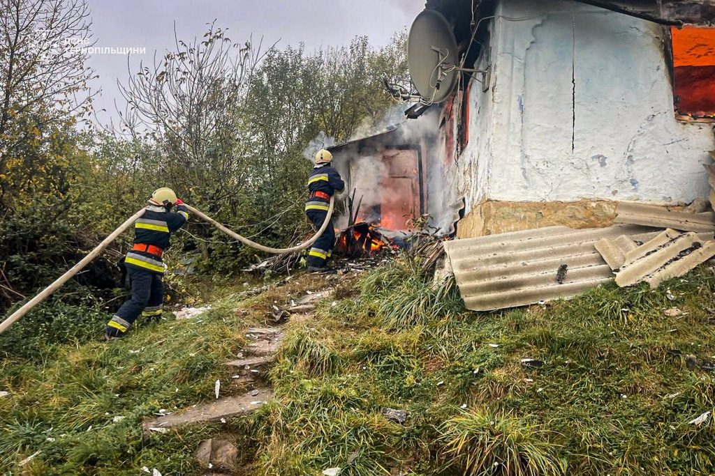 модель обпаленого будинку поруч із шоломом пожежника та шлангом, без людей