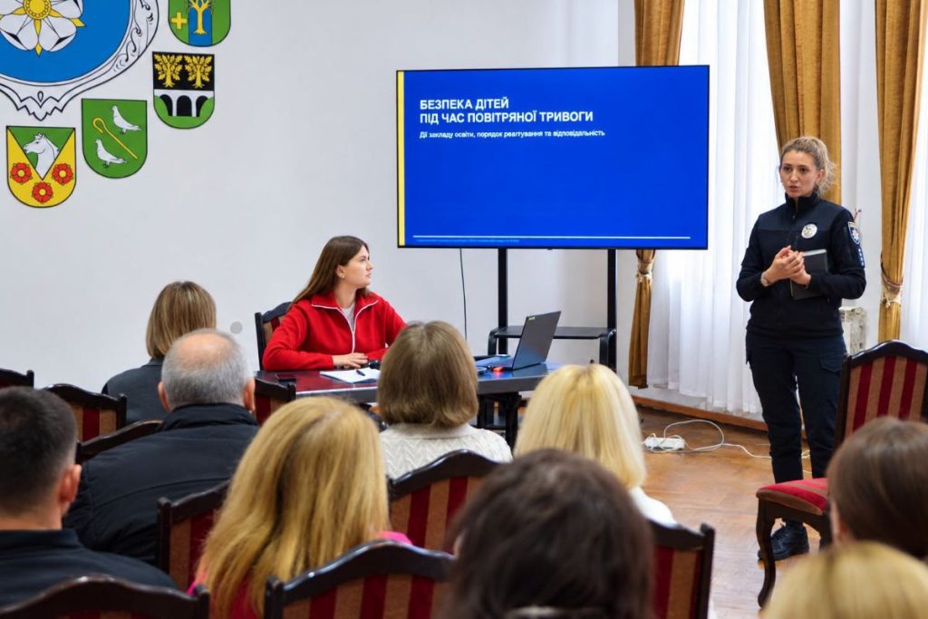 символічна сцена підготовки школи до надзвичайної ситуації: запаси, каски і ліхтар біля дверей в укриття, без людей