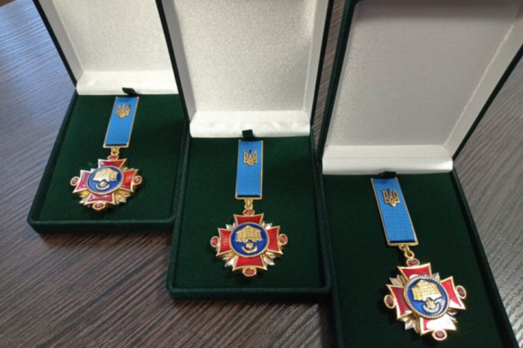 символічне натюрморт із складеним українським прапором, військовими знаками та зверненим сертифікатом на деревʼяному фоні