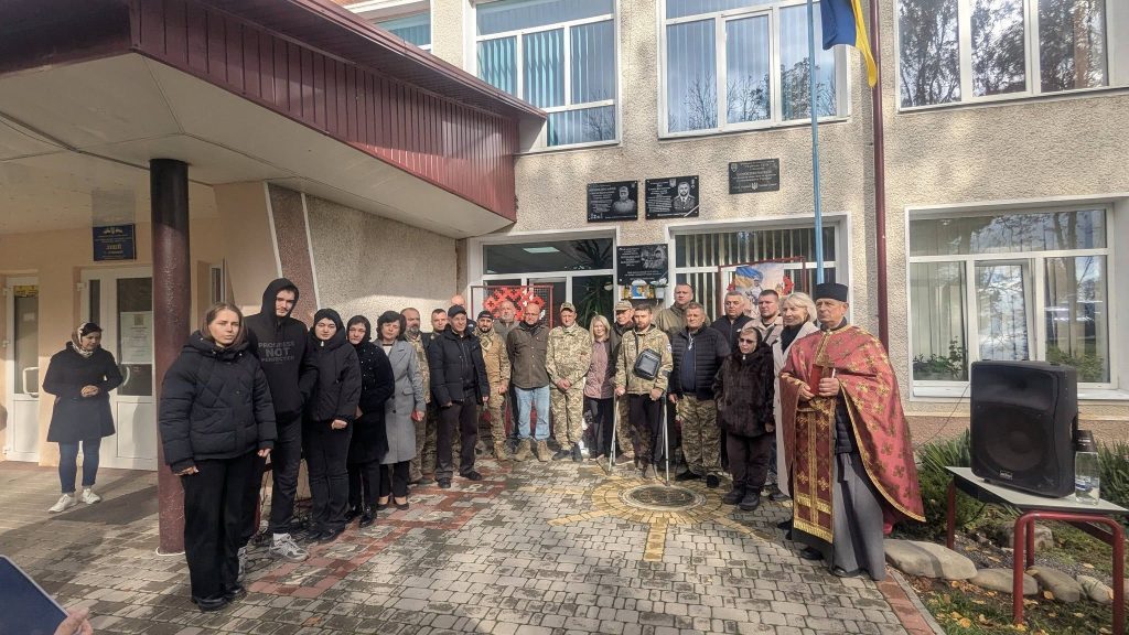 Символічна предметна сцена з нагрудним жетоном на шкільному зошиті та квіткою