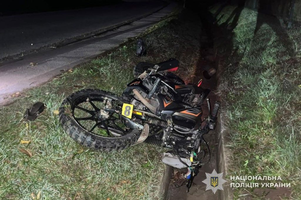 Шолом від скутера та ключ від автомобіля на мокрому асфальті