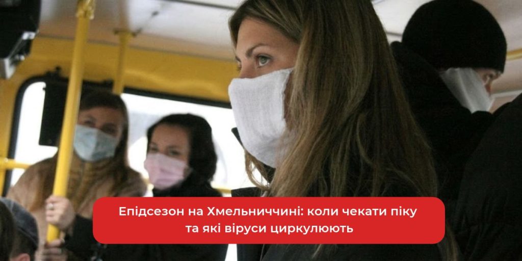 флакон вакцини та медична маска на дерев'яному столі, на задньому плані стетоскоп і папери