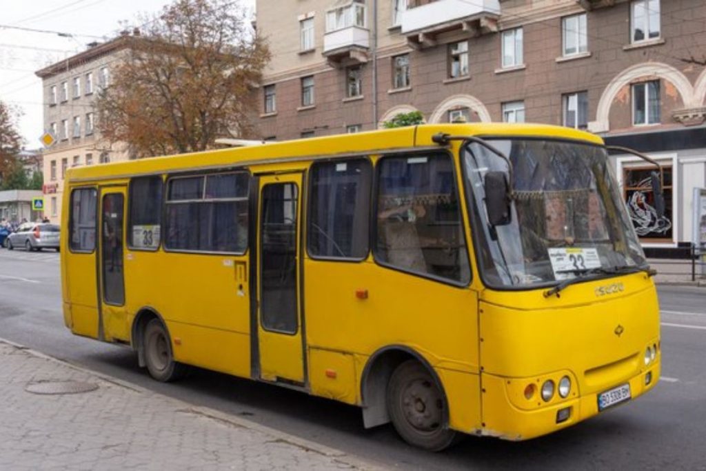 Електронне інформаційне табло з іконками автобусів і розкладом, на розмитому міському фоні