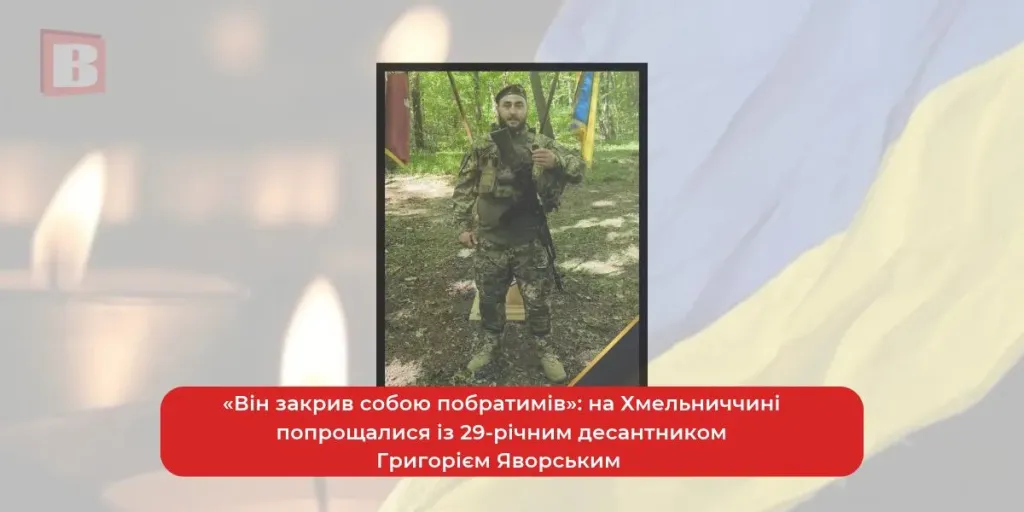 складений жетон, поношена каска й маленький український прапор на деревʼяному столі