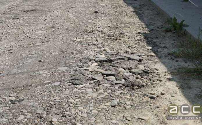 згорнутий план дороги, зразок асфальту і макет вуличного знака на столі