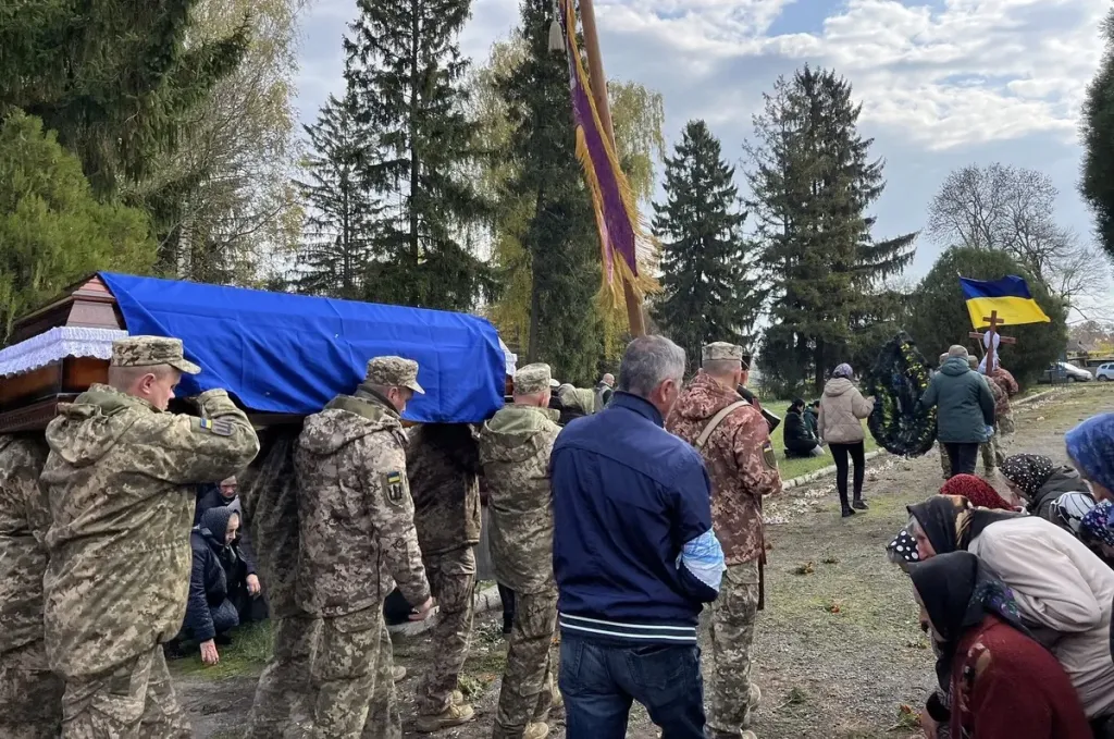 Символічна меморіальна сцена з кашкетом, свічкою та квітами.