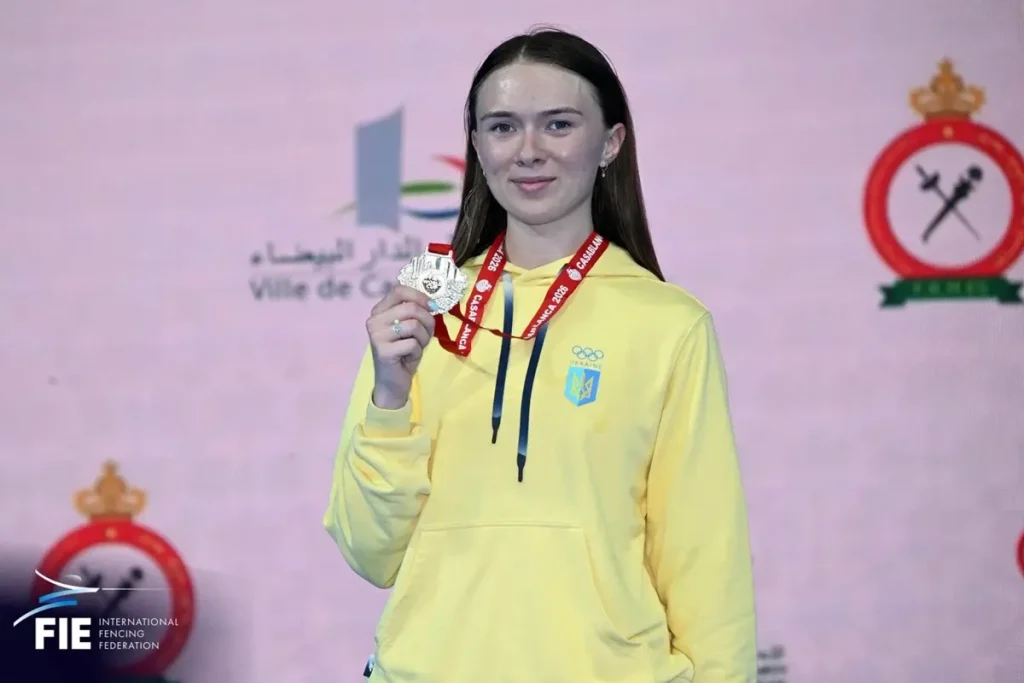 Крупний план шпаги й бронзової медалі на мінімалістичному тлі