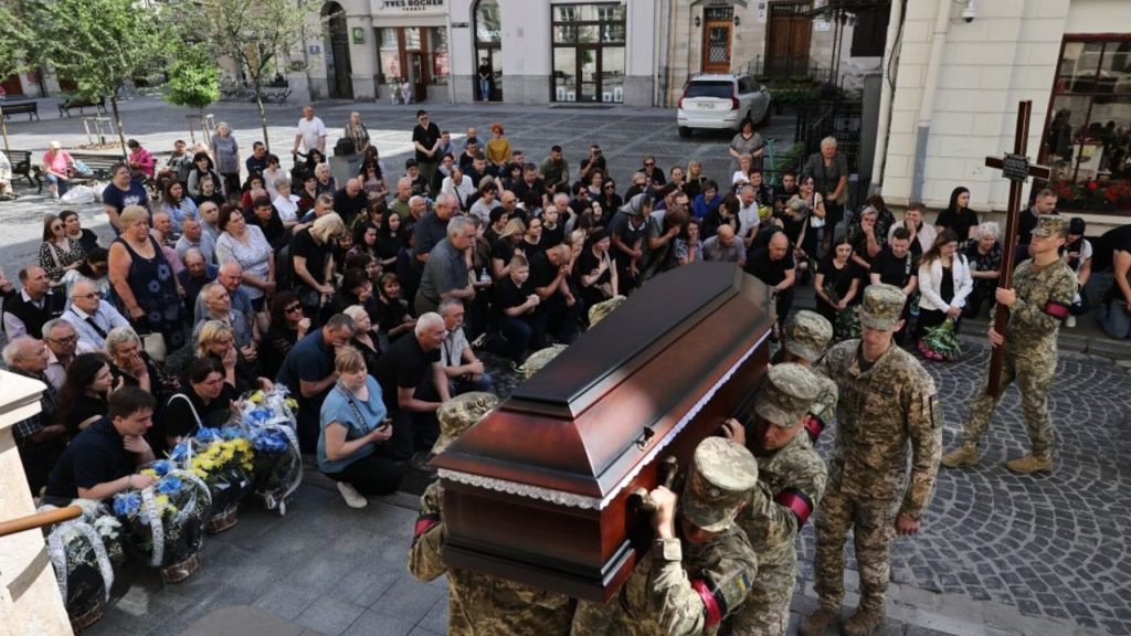 символічна сцена з запаленою свічкою, пустою рамкою для фото, каскою та квіткою ромашки