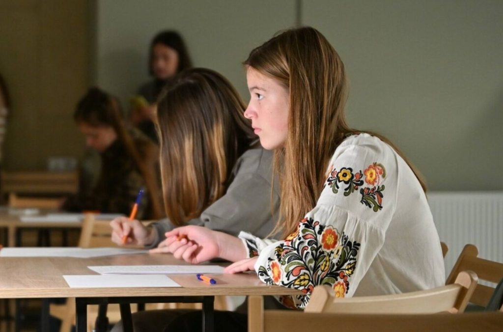 Крупний план рук, які пишуть у блокноті поряд із радіо та чашкою чаю, без осіб