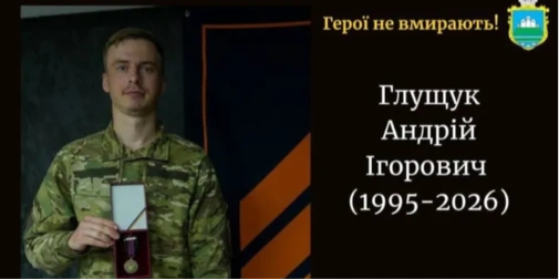 складений прапор, бойовий шолом і запалена свічка на дерев’яному столі