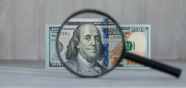 Українські банкноти та монети поруч із календарем на дерев'яному столі