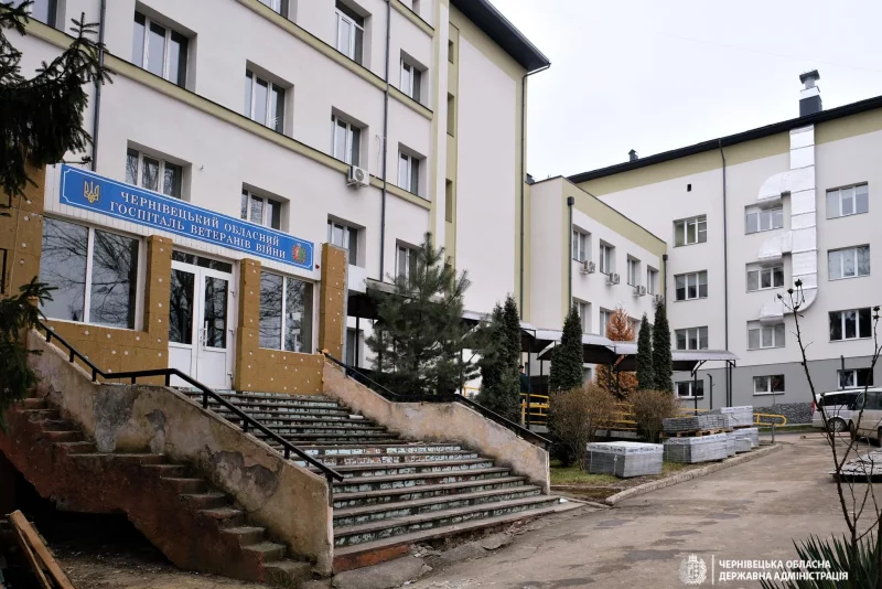 натюрморт із елементами медицини й реабілітації: модель лікарні, частини протеза, бинти і папки на нейтральному тлі