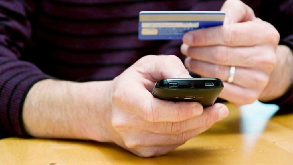 символічна натюрморт-сцена: ключ від трактора, смартфон із повідомленням і купюри на дерев'яному столі