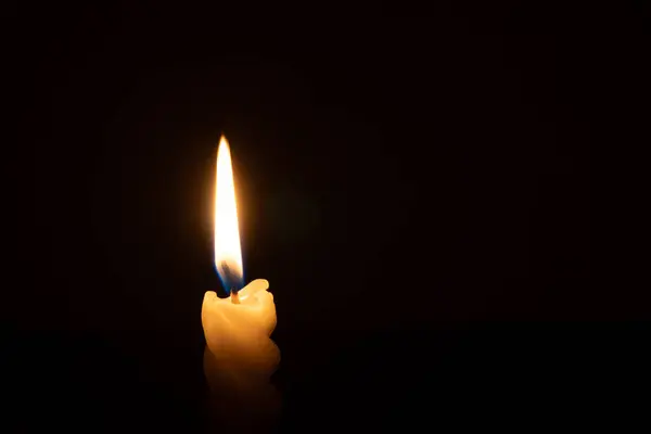 символічна композиція із складеним військовим одягом, шоломом і запаленою свічкою