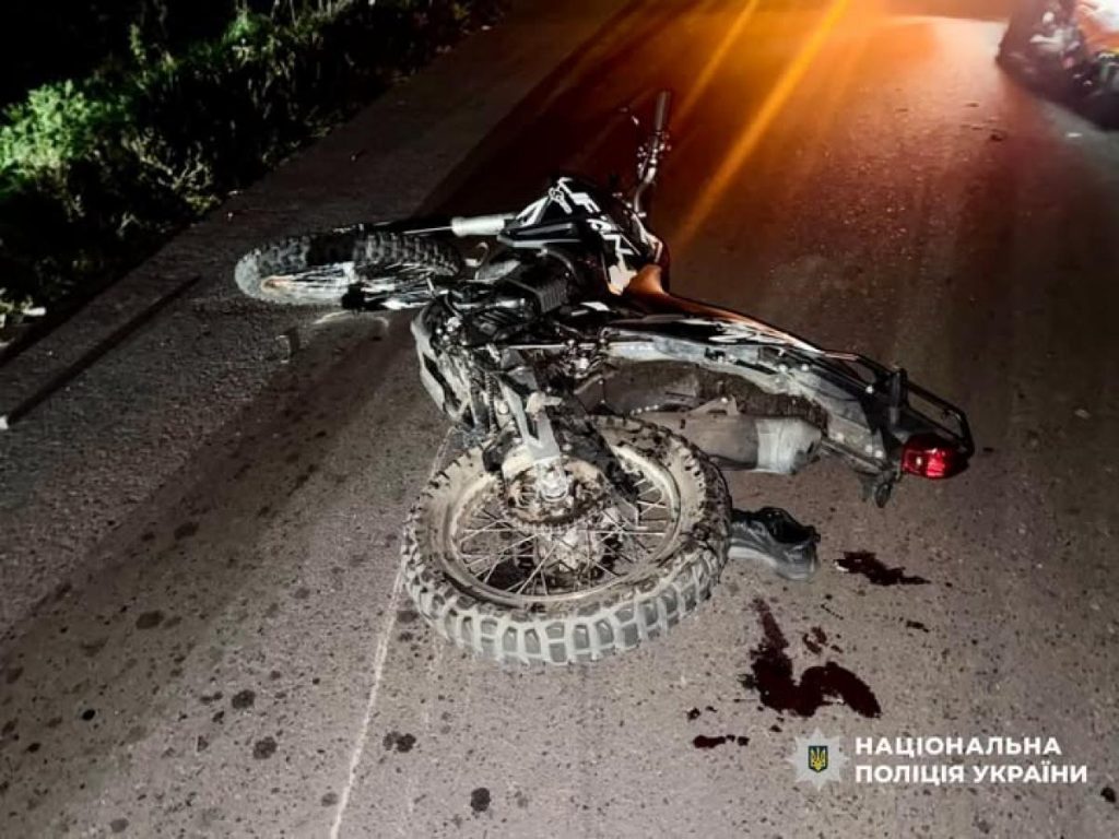 символічна сцена: мотошолом на узбіччі біля дороги ввечері поруч ключі і куртка