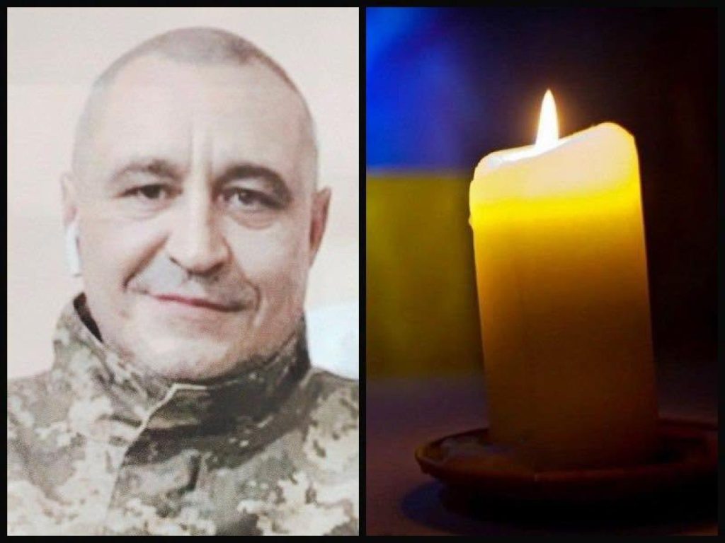 символічна сцена: складена військова форма і свічка на дерев'яному столі