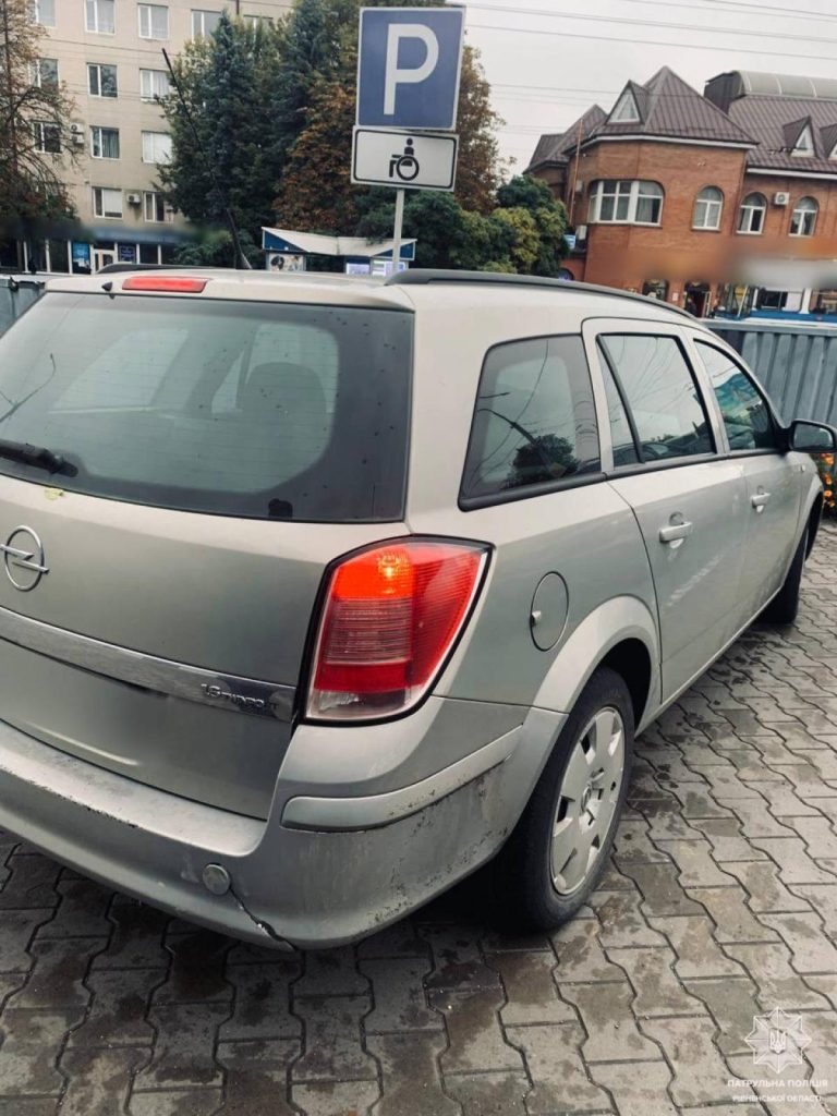 маркірована паркомісце для інвалідів з авто та постановою на лобовому склі, супермаркет розмите на фоні