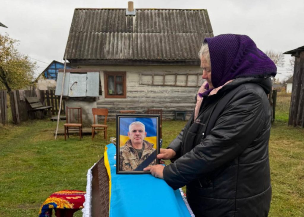 запалена свічка поруч зі складеним прапором на деревʼяній поверхні, мʼяке сумне освітлення
