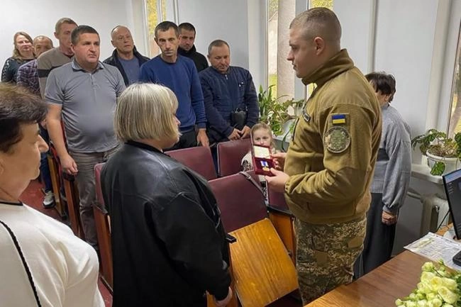 медаль на складеному українському прапорі, символічна сцена без облич
