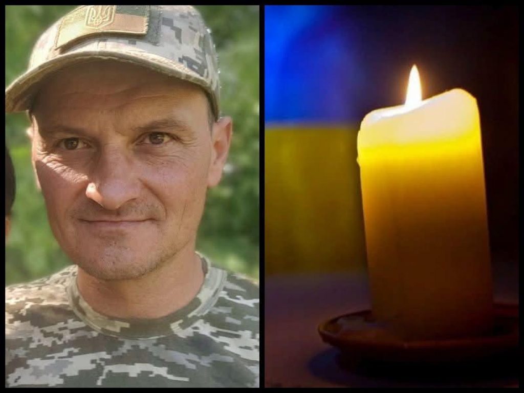запалена свіча поруч зі складеним шарфом та старою світлиною на дерев’яному тлі