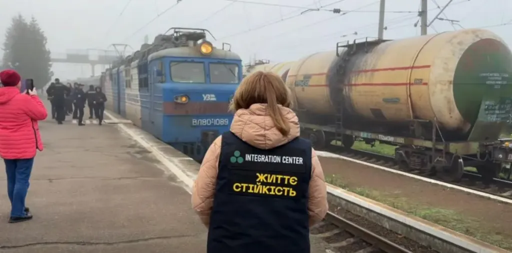 Символічна сцена: складені пледи, дитяча іграшка та паперова карта на столі, без облич